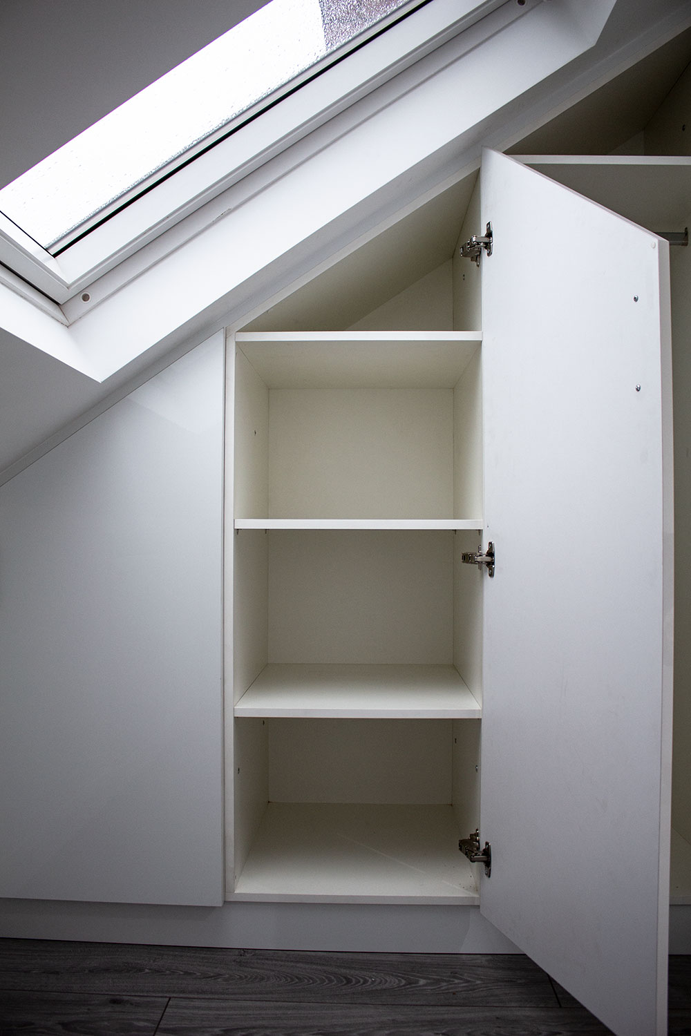 Fitted loft wardrobe with open door, revealing shelves